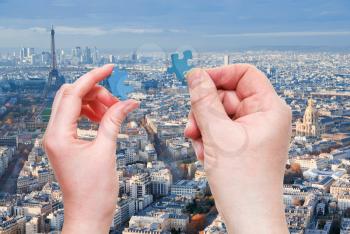male and female hands with little puzzle pieces with Paris district and Eiffel Tower background
