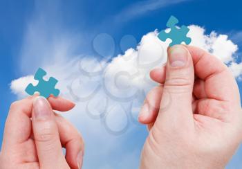 male and female hands with little puzzle pieces with blue sky with white clouds background