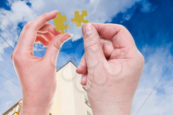 male and female hands with little puzzle pieces with blue sky and urban house background