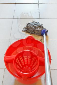 mopping the tile floor by swab and red bucket with foamy water