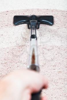 man vacuuming the carpet by vacuum cleaner at home