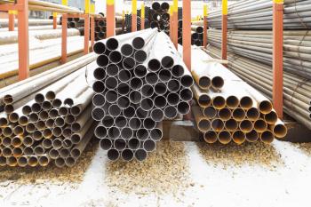 piles of steel pipes in outdoor warehouse in winter