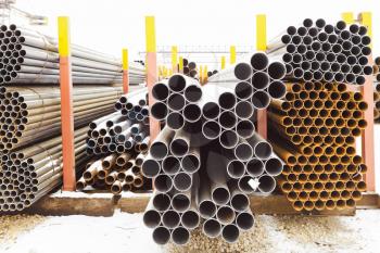 piles of different metal pipes in outdoor warehouse in winter