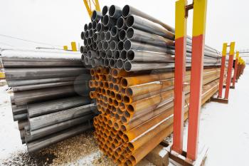 pile of construction pipes in outdoor warehouse in winter