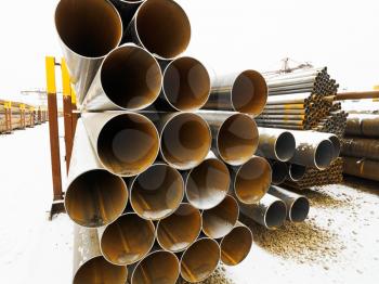 heap of steel pipes in outdoor warehouse in winter