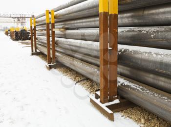 stacks of construction pipes on outdoor warehouse in winter