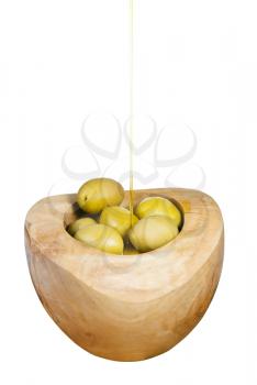 olive oil trickles on green olives in wooden bowl close up isolated on white background