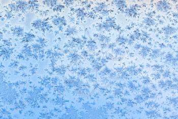 snowflakes and frost pattern on window with blue sky background