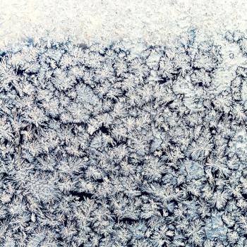 winter background - snowflakes and frost on frozen window pane