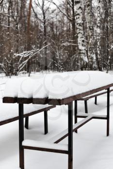 snow-covered table in city park in winter