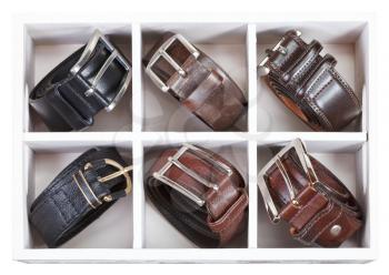 leather belts in wooden storage box isolated on white background