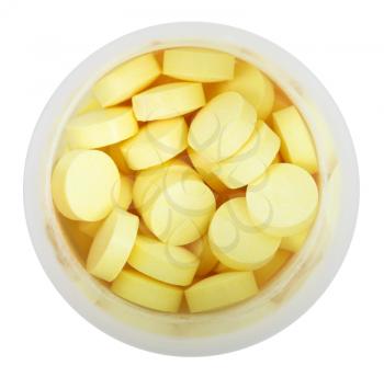 yellow pills in round plastic bottle close up isolated on white background