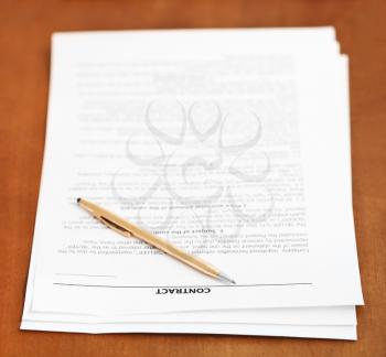 sheets of sales contract and golden pen on wooden table