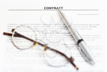 silver pen and eyeglasses on page of sales agreement