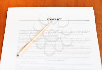 golden pen on sheet of sales contract on wooden table