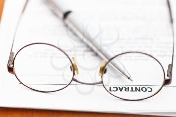sales contract and silver pen through eyeglasses