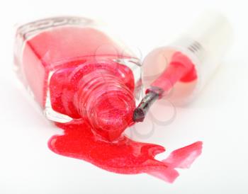 bottle with spilled red nail polish on white background