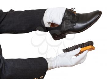 Shoeshiner in white gloves cleaning black shoes by brush isolated on white background