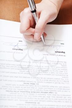 client signs a contract by silver pen on table