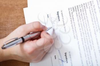 customer signs a contract by silver pen on table