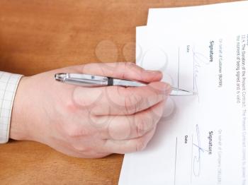 businessman signs a contract by silver pen on table