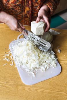 woman shredding cabbage by manual slaw cutter on table