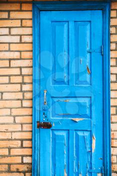 closed shabby blue wooden door in brick wall