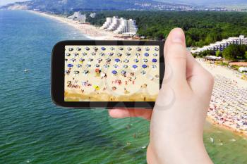 travel concept - tourist taking photo of aerial view of Albena sand beach on mobile gadget, Bulgaria
