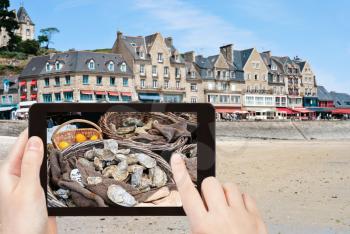 travel concept - tourist taking photo of waterfront of town Cancale in summer day. This town is oyster capital of Brittany, France