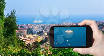 travel concept - tourist taking photo of ships near Cannes town on mobile gadget, France