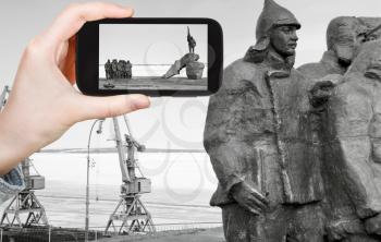 travel concept - tourist taking photo of Memorial First Revolutionary Committee (Revcom) of Chukotka on mobile gadget, Anadyr, Russia