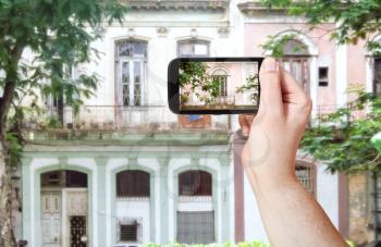 travel concept - tourist taking photo of old building in Havana on mobile gadget, Cuba
