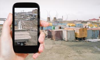 travel concept - tourist taking photo of street market and pipeline in Anadyr town on mobile gadget, Chukotka, Russia