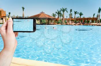 travel concept - tourist taking photo of children swimming in pool on mobile gadget, Egypt
