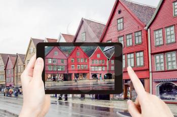 travel concept - tourist taking photo of Bryggen quay in Begen on mobile gadget, Norway