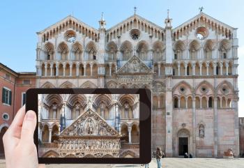 travel concept - tourist taking photo of Ferrara Cathedral, Italy on mobile gadget
