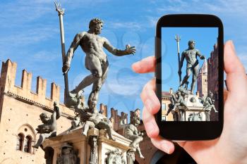 travel concept - tourist snapping photo of fountain of neptune in Bologna on mobile gadget, Italy
