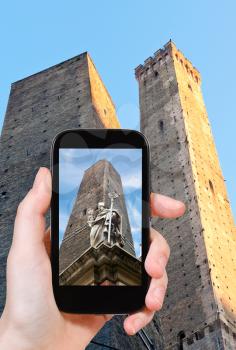 travel concept - tourist taking photo of saint petronius statue and two tower in Bologna on mobile gadget, Italy