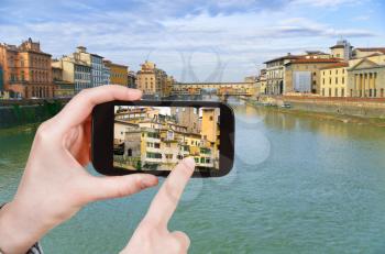 travel concept - tourist taking photo of Ponte Vecchio on Arno river in Florence on mobile gadget