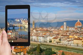 travel concept - tourist taking photo of Ponte Vecchio in Florence on mobile gadget, Italy