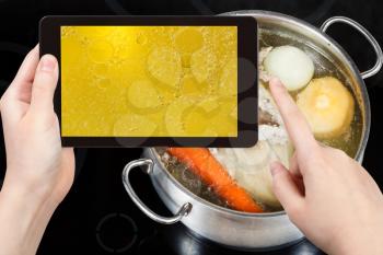 photographing food concept - tourist taking photo of boiling of chicken broth on mobile gadget