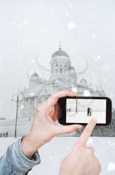 travel concept - tourist taking photo of Helsinki Cathedral in winter on mobile gadget, Finland