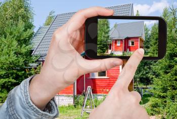 travel concept - tourist taking photo of new small country house on mobile gadget