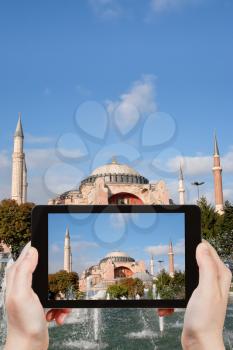 travel concept - tourist taking photo of Haghia Sophia through fountain on Sultanahmet square on mobile gadget, Istanbul, Turkey
