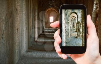 travel concept - tourist taking photo of ancient arcades in Temple of Jupiter Anxur (youth) in Terracina town on mobile gadget, Italy