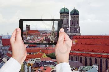 travel concept - tourist taking photo of two tower Frauenkirche in Munich on mobile gadget, Germany