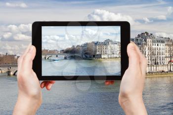 travel concept - tourist taking photo of Seine river and Pont Louis-Philippe in Paris on mobile gadget, France