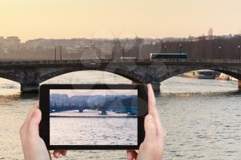 travel concept - tourist taking photo of bridges in Paris on yellow blue sunset on mobile gadget