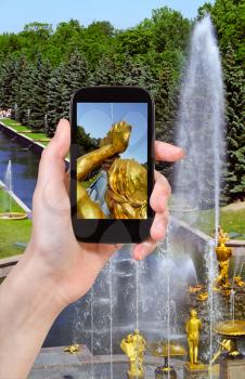travel concept - tourist taking photo of Samson Fountain and Sea Channel in Petergof on mobile gadget, Russia