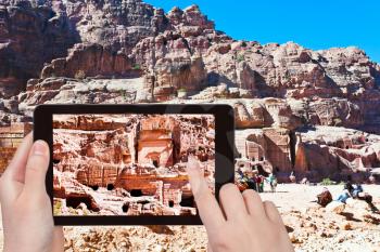 travel concept - tourist taking photo of tombs and houses in stone city Petra, Jordan on mobile gadget